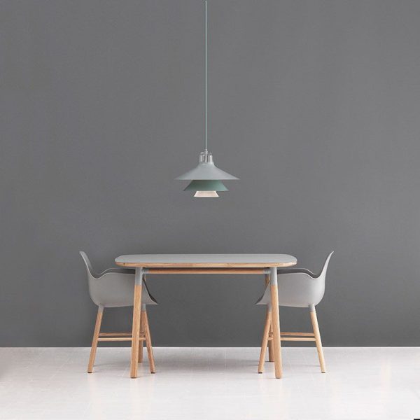 En minimalistisk spisestue har et træbord med metalben, flankeret af to grå moderne stole, under en grøn hængende pendel mod en almindelig grå væg. Denne opsætning viser elementer af TomorrowsDesign.