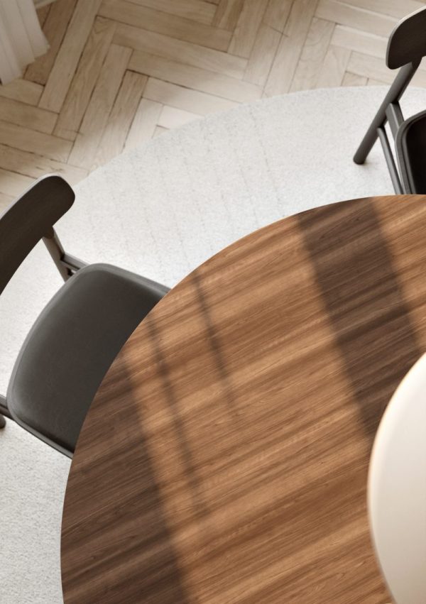 Set ovenfra og ned af en moderne spiseplads med et rundt træbord med en delvis hvid dug og stole med mørke hynder, sat på et mønstret trægulv af TomorrowsDesign.