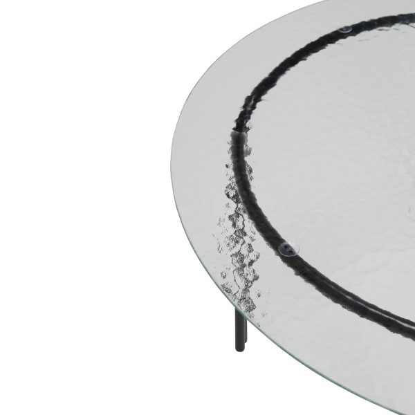 Set ovenfra af et moderne rundt glas sofabord med en minimalistisk sort TomorrowsDesign-detalje på overfladen og tre sorte metalben. Baggrunden er helt hvid, hvilket understreger bordets enkelthed og moderne stil.