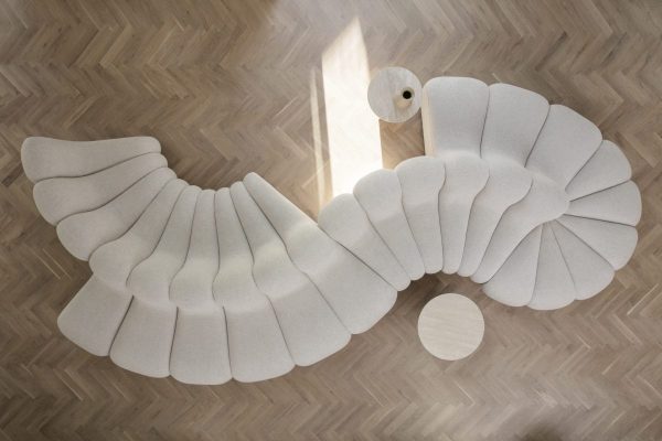 Et kreativt tæppe designet til at ligne en abstrakt svane, med lag af gråt stof, der efterligner fjer, vist på et sildebenstrægulv af TomorrowsDesign.