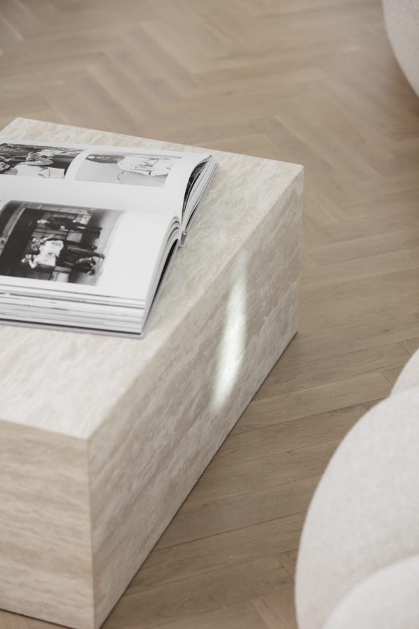 Et åbent fotoalbum med sort/hvide billeder ligger på et marmormønstret sofabord i et værelse med trægulv og en del af en hvid sofa synlig på siden, hvilket er indbegrebet af TomorrowsDesign-æstetik.
