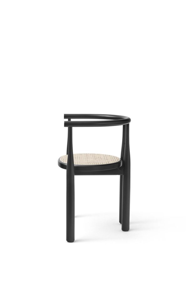 En minimalistisk sort stol med buet ryglæn og vævet sæde, sat mod en ensfarvet hvid baggrund og har en elegant designmøbler-stil.