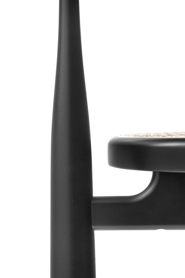 Nærbillede af en sort stol med minimalistisk design, med en glat, mat finish og en vævet sædedetalje fra TomorrowsDesign, isoleret på en hvid baggrund.