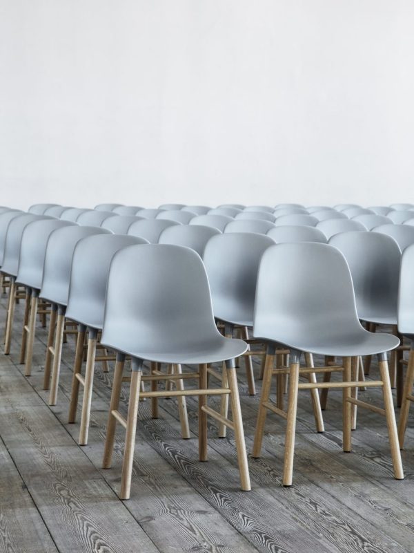 Rækker af moderne grå stole med træben, designet af TomorrowsDesign, pænt afstemt i et rummeligt værelse med lyst trægulv og hvid vægbaggrund.