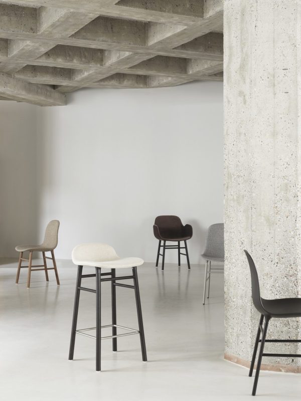Fire moderne stole med forskellige designs arrangeret i et sparsomt rum i industriel stil med synlige betonvægge og loft af TomorrowsDesign.