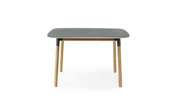Et moderne bord med en rektangulær, mørkegrå overflade oven på fire slanke træben fra TomorrowsDesign, isoleret mod en hvid baggrund.