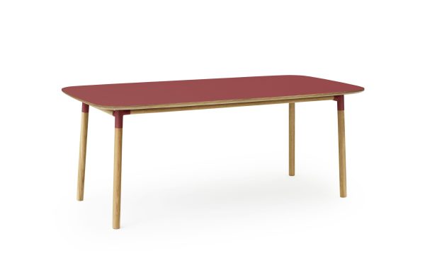 Et moderne bord med rødbrun rektangulær plade og naturlige trækanter, stående på fire slanke, vinklede træben. Baggrunden er almindelig og hvid, hvilket understreger bordets interiørdesign.