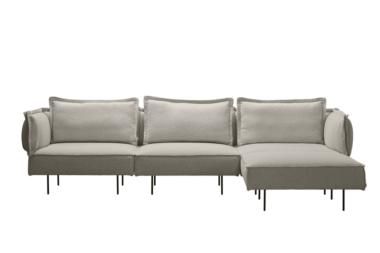 A HANDVÄRK MØBLER - Modulsofaen m. Chaiselong, Cloud med plyspuder og slanke, sorte ben, isoleret på en sort baggrund.