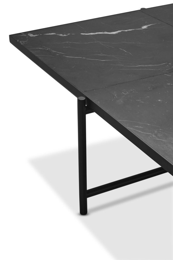 Et moderne minimalistisk bord med en tynd, mørk marmorplade og et robust sort metalstel, placeret på en almindelig hvid baggrund for at understrege skarpe kontraster og slankt TomorrowsDesign.