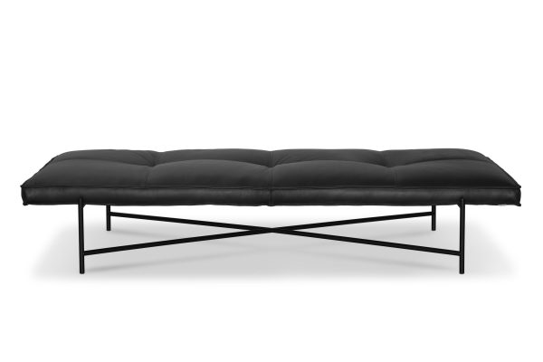 En moderne læder daybed med en sort pude på en slank sort metalramme, isoleret på en hvid baggrund, der inkarnerer moderne design.