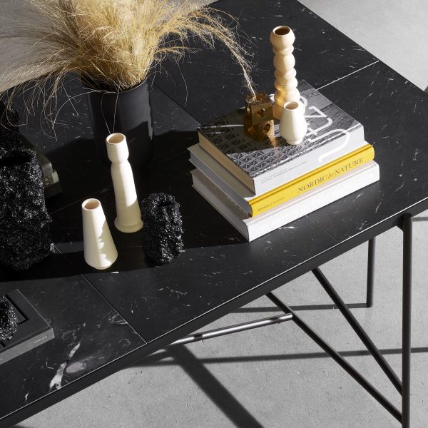 En stilfuld indretningsscene med et marmorsofabord prydet med bøger med titlen "Nordic Adventures", forskellige hvide vaser og sorte geometriske skulpturer. En tott prydgræs tilføjer et naturligt præg, suppleret med TomorrowsDesign-elementer.