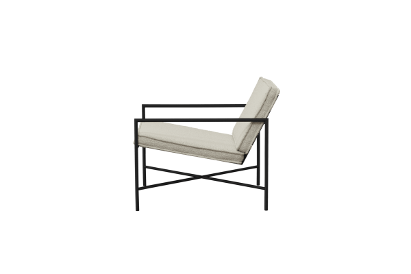 En moderne lænestol med sort metalstel og cremepuder sat på en solid grøn baggrund fra TomorrowsDesign.