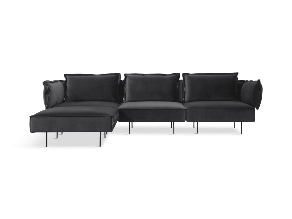 En moderne sort sektionssofa med plyshynder og en chaiselong i venstre side, sat mod en solid grøn baggrund. Dette designstykke løfter ethvert rum med sin moderne æstetik.