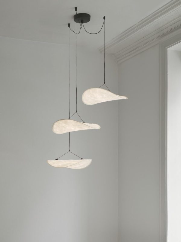 Tre Tense Chandelier Ø55 pendellamper med organiske former hænger fra sorte ledninger i et rum med hvide vægge og dekorativ kroneliste.