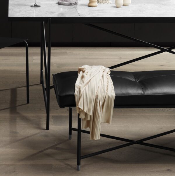 En cremefarvet plisseret bluse draperet over ryggen på en moderne sort spisestuestol med tynde metalben, designet af TomorrowsDesign, sat ved et mørkt marmorbord i et værelse med slanke, polerede gulve.