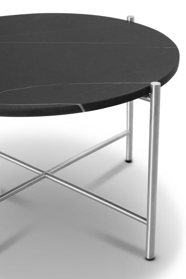 Et moderne cirkulært sort sofabord med en slank metalramme og en nederste hylde, med moderne design, sat mod en hvid baggrund.