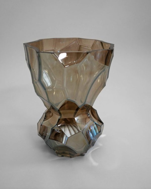 A HEIN STUDIO - Reflection Vase - Metallic med et geometrisk design på en almindelig grå baggrund. Vasen har en udpræget kantet form, der indsnævres i bunden og udvides mod toppen.