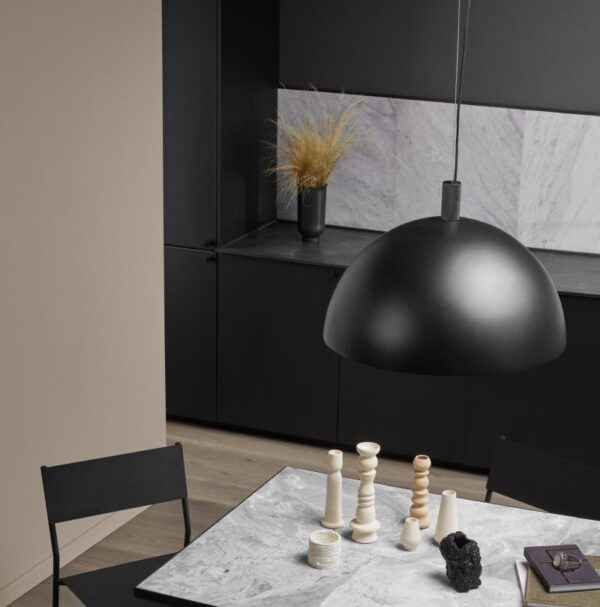 En minimalistisk spisestue med et sort og hvidt farveskema. En stor kuppelformet pendel fra TomorrowsDesign hænger over et marmorbord med moderne dekorative genstande. Sorte skabsværker langs væggen.