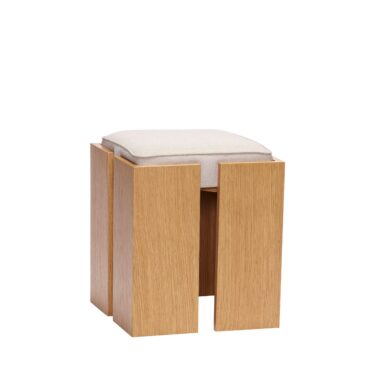 En moderne trætaburet med et lys beige polstret sæde, med et simplistisk firkantet design med synlige sidepaneler. Taburetten er sat mod en almindelig hvid baggrund og er et eksempel på minimalistisk interiørdesign.