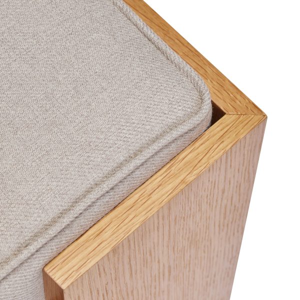 Nærbillede af en designer træstol med en beige pude, der viser detaljeret tekstur af egetræsrammen og pudens stof.