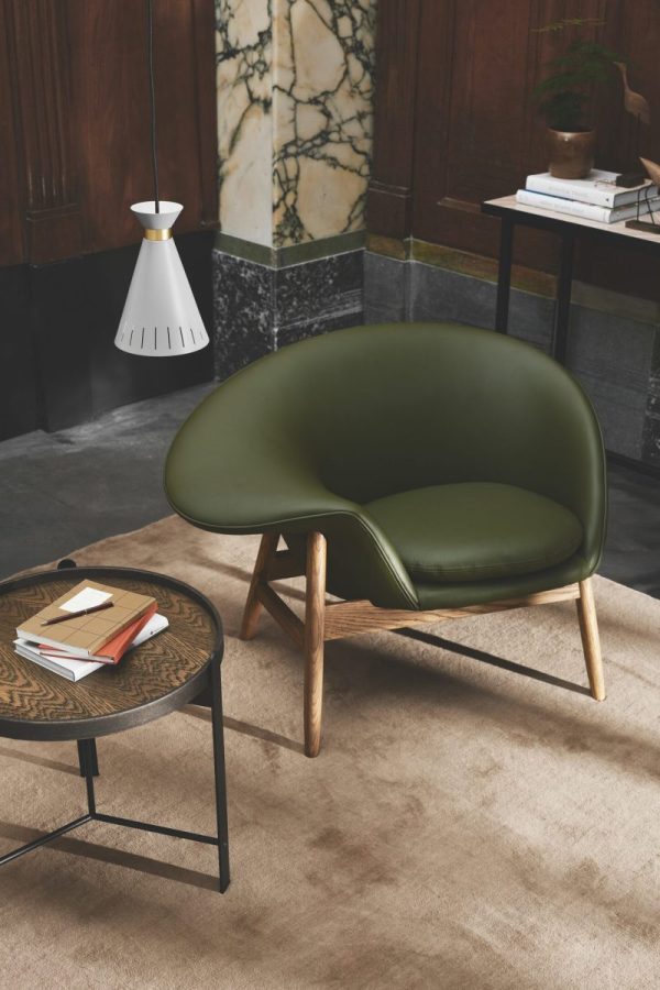 Moderne, minimalistisk opholdsstue med en elegant grøn stol med træben, et lille rundt sofabord med bøger og en hvid pendel, sat på baggrund af marmor og mørke fliser. Denne indstilling eksemplificerer essensen af TomorrowsDesign i alle detaljer.