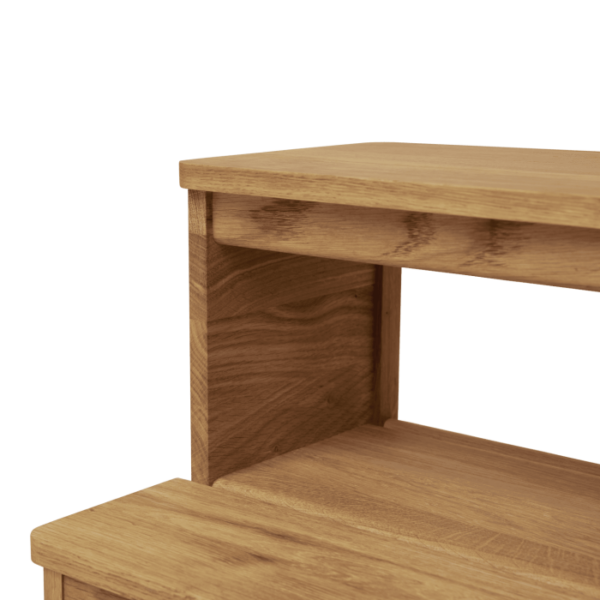 Et nærbillede af et hjørne af et minimalistisk træbord, der viser bordets rene linjer og naturlige træårer, sat mod en sort baggrund. Ideel til elskere af designmøbler.