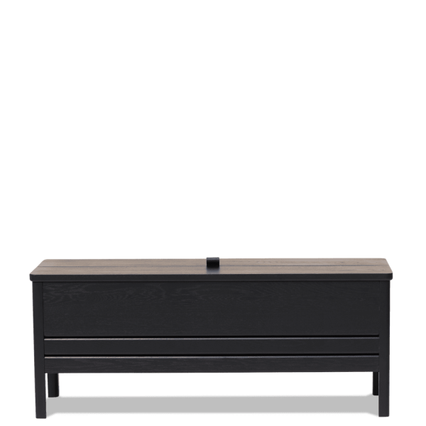 En sort træbænk med et fladt sæde og et hængslet låg, der viser vandret panel og en minimalistisk designmøbler, sat mod en solid grøn baggrund.
