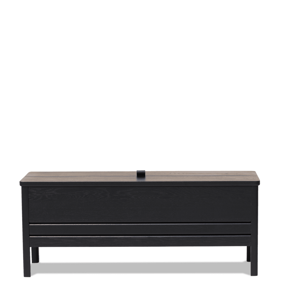 En sort træbænk med et fladt sæde og et hængslet låg, der viser vandret panel og en minimalistisk designmøbler, sat mod en solid grøn baggrund.