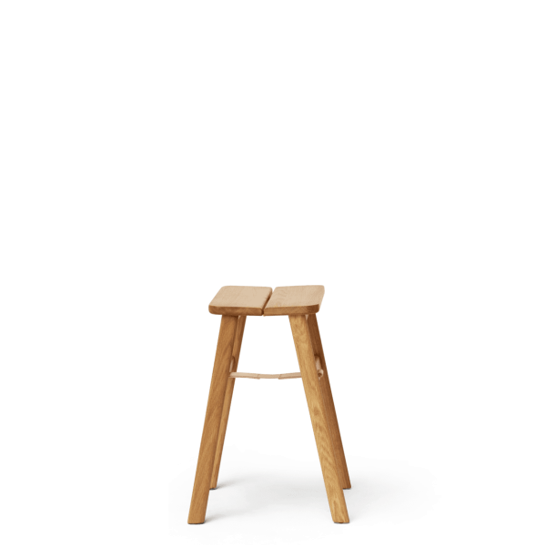 En træskammel med en enkel, rustik designmøbler, med en flad top understøttet af tre spredte ben, sat mod en solid grøn baggrund.