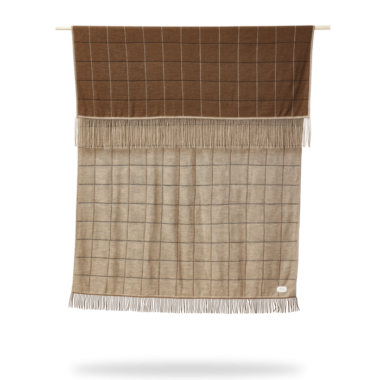 A FORM & REFINE - Aymara Plaid New Square 130x190 tæppe med frynser, hængende lodret mod en hvid baggrund.