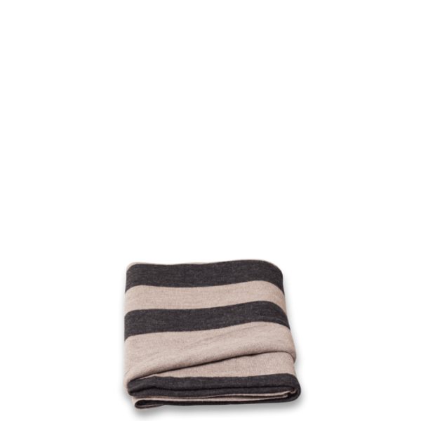 En foldet FORM & REFINE - Aymara Plaid Ribbon 190x130 i nuancer af beige og sort, sat mod en sort baggrund.