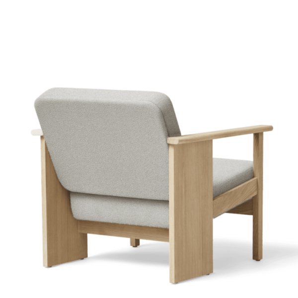 En moderne lænestol med lysegrå polstring og massivt træstel, vist mod en almindelig sort baggrund. FORM & REFINE - Block Lænestol Grain har et forenklet design med rene linjer og synlige træarmlæn.