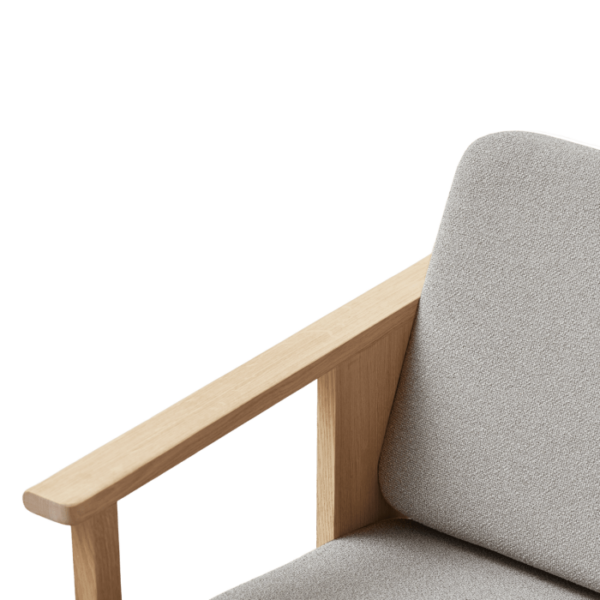 Nærbillede af en FORM & REFINE - Block Lænestol Grain med en lys træramme og gråt polstring, sat mod en sort baggrund.