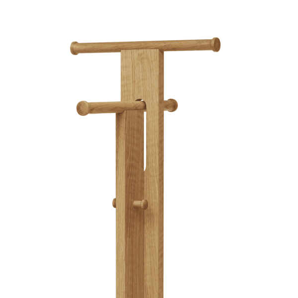 A FORM & REFINE - Foyer Stumtjener med to vandrette pløkker, stående mod en solid grøn baggrund. dens design er enkelt og funktionelt, lavet af et lyst træ.