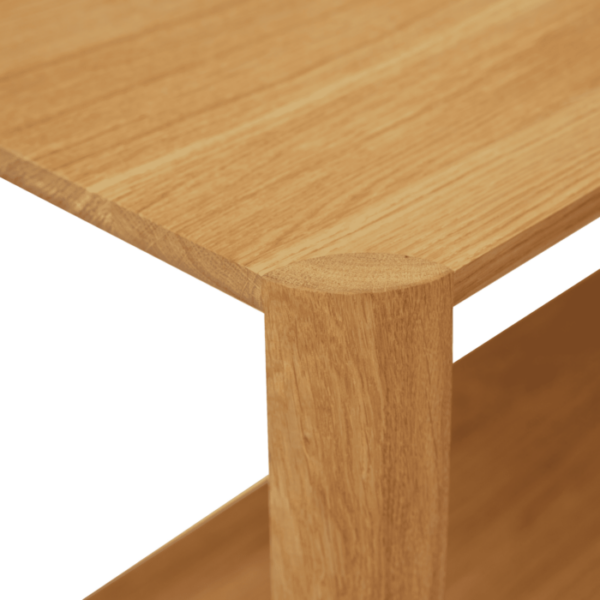 Hjørne af en FORM & REFINE - Leaf Reol 1x3, der viser den glatte overflade og et robust ben, sat mod en gennemsigtig baggrund. træet har et naturligt åremønster med en varm tone.