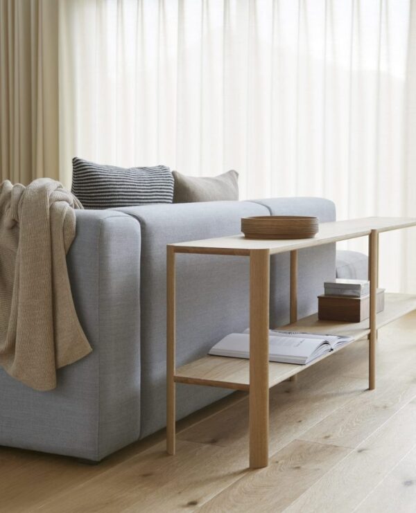 Et moderne stuehjørne med en lysegrå sofa med hvidt læg og en sort pude ved siden af et sofabord af træ på et lyst hårdttrægulv. lysgardiner i baggrunden. - FORM & FORFIN - Afsnit Træskål