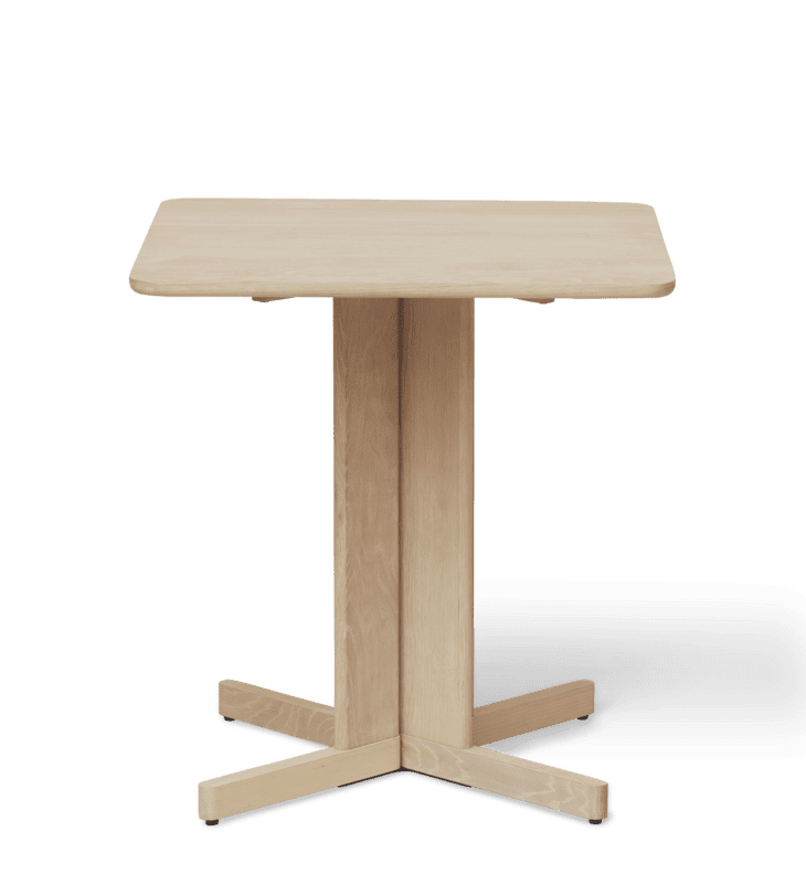 A FORM & REFINE - Quatrefoil Bord 68x68 med en rektangulær top og en krydsformet base, isoleret på en sort baggrund. bordet er lavet af lyst træ og har et enkelt, moderne design.