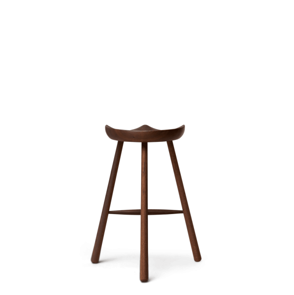 A FORM & REFINE - Skomager Barstol nr. 68 med et buet sæde står mod en solid grøn baggrund. skamlen har tre ben og en rig, mørk finish, der kaster en lille skygge direkte under den.