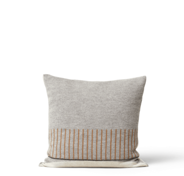 En dekorativ pude med et tofarvet design med en beige øvre halvdel og en nedre halvdel prydet med lodrette solbrune striber, sat mod en almindelig sort baggrund FORM & REFINE - Aymara Pude Mønster.