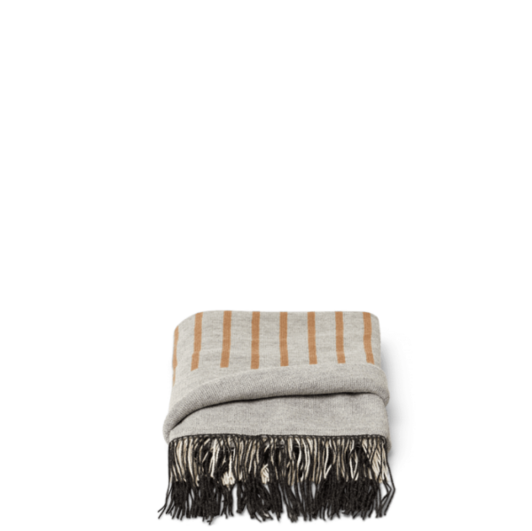 Et foldet FORM & REFINE - Aymara Plaid Mønster 190x130 tæppe med sorte frynser, vist mod en sort baggrund.