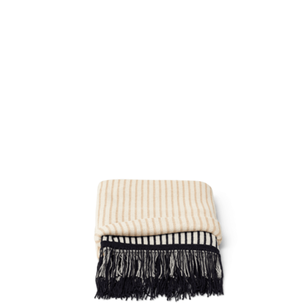 Et foldet FORM & REFINE - Aymara Plaid Stripes 190x130 tæppe med sorte frynser detaljer på kanterne, isoleret på en sort baggrund.
