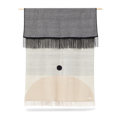 Et vægophæng med et minimalistisk design med geometriske former i neutrale toner er ophængt i en trædyvel og har frynsede kanter. FORM & REFINE - Aymara Plaid Mønster 190x130 inkluderer en sort cirkel på en beige og grå baggrund.