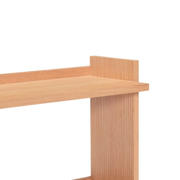 Nærbillede af et moderne træbord med et enkelt design, der viser et hjørne, hvor den øverste overflade møder det lodrette ben, isoleret på en almindelig hvid baggrund.