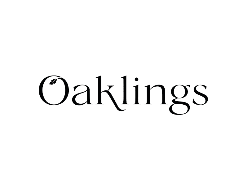 Billedet viser ordet "Oaklings" i sort serif-skrifttype på en hvid baggrund. Bogstavet "O" i "Oaklings" har et lille egeblad fastgjort til sin indre kurve.